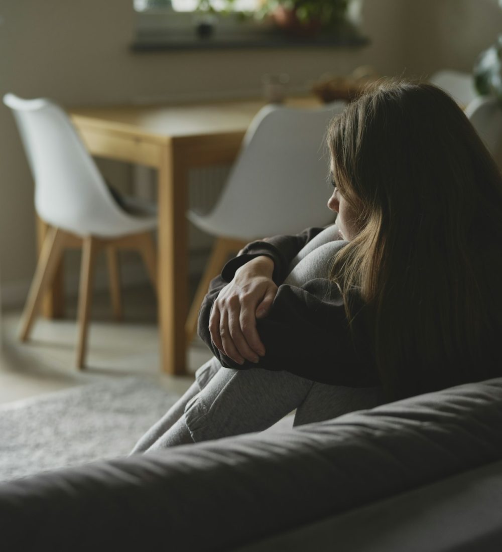 Caucasian sad woman sitting at the sofa with depression