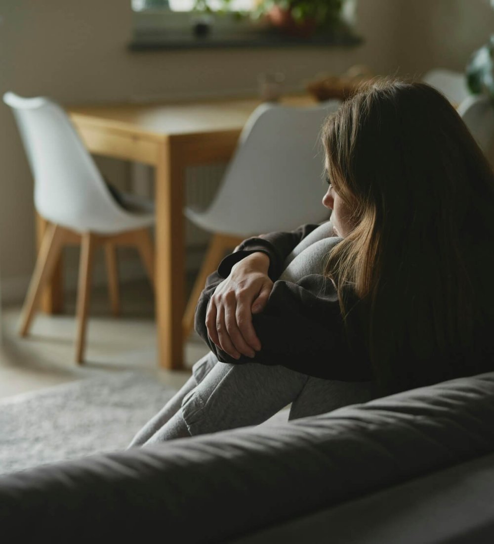 Caucasian sad woman sitting at the sofa with depression