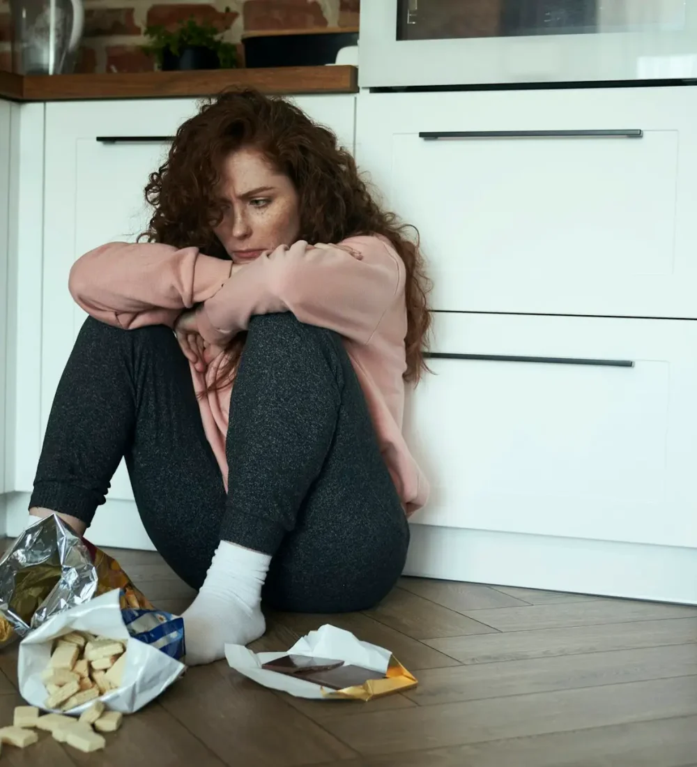 Young caucasian woman with eating disorder eating greedily on the floor